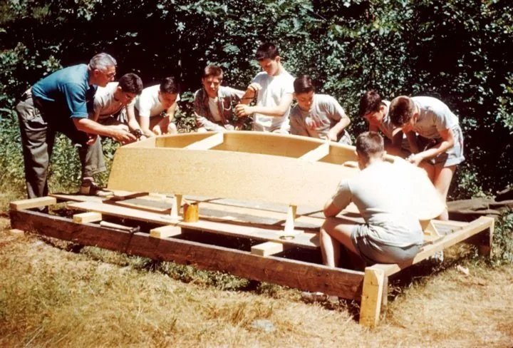 Volunteers building a wooden boat at Camp Wigwam