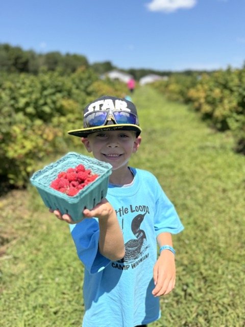 A Little Loon proudly holding a pint of fresh-picked raspberries at Pineland Farms