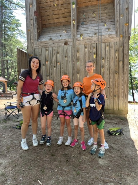 Little Loons in helmets and harnesses posing in front of the climbing tower