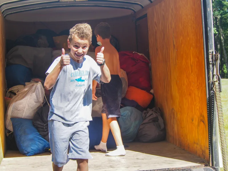Open trunk packed with clothing, bedding, and gear for a Camp Wigwam summer session