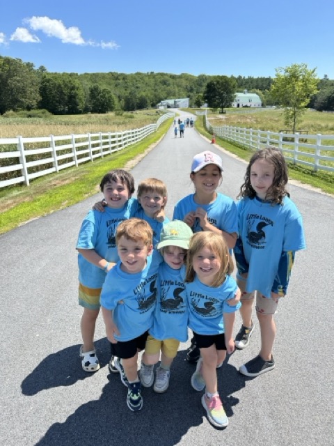 A group of Little Loons in matching tees posing on the road at Pineland Farms