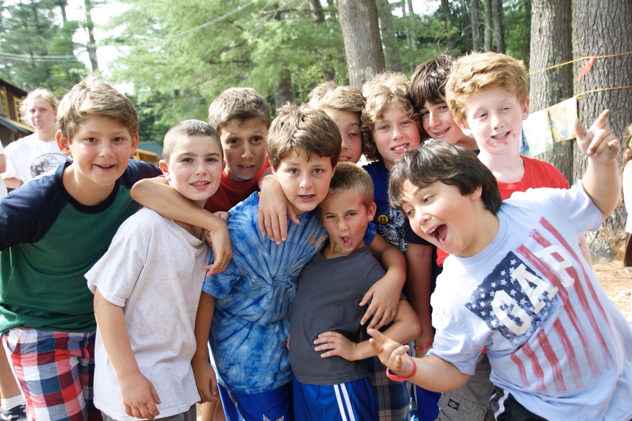 Group of Camp Wigwam boys laughing and posing together in the pines during an afternoon activity