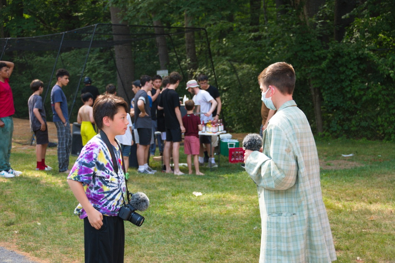 Young camper being interviewed on camera with a boom mic during the Wigwam film studio activity