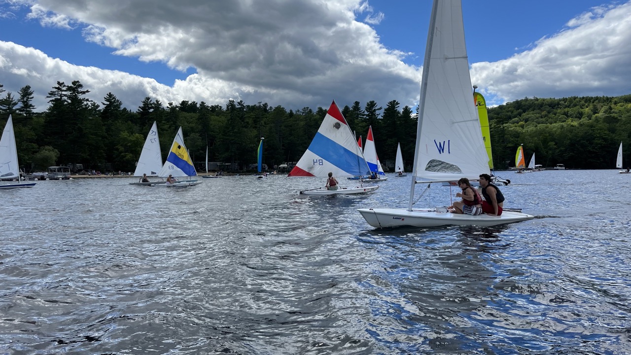 Fleet of colorful sailboats with campers tacking across Bear Lake on a breezy summer day