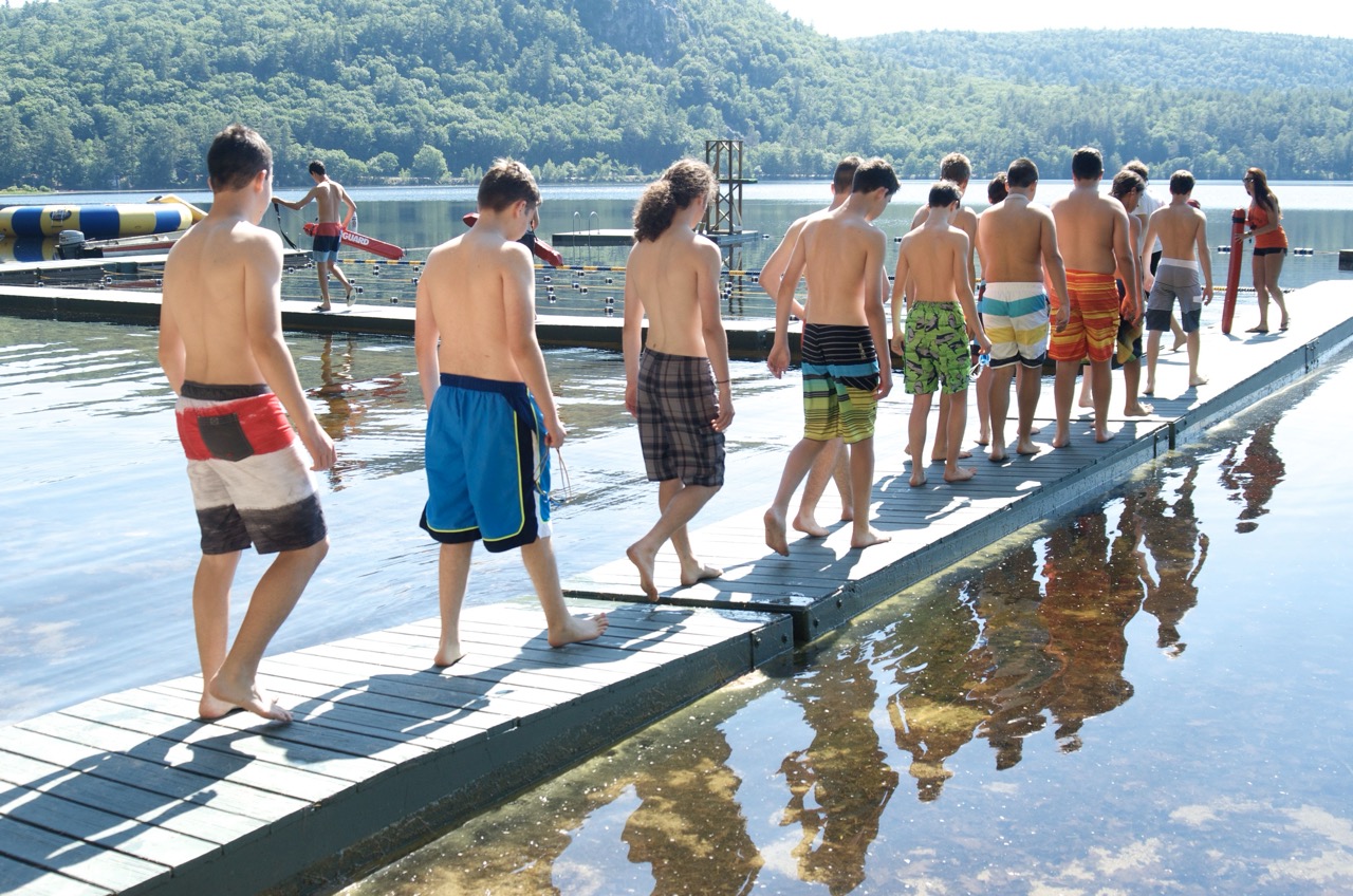 Line of campers walking single-file along the swim docks during morning swim lessons at the waterfront
